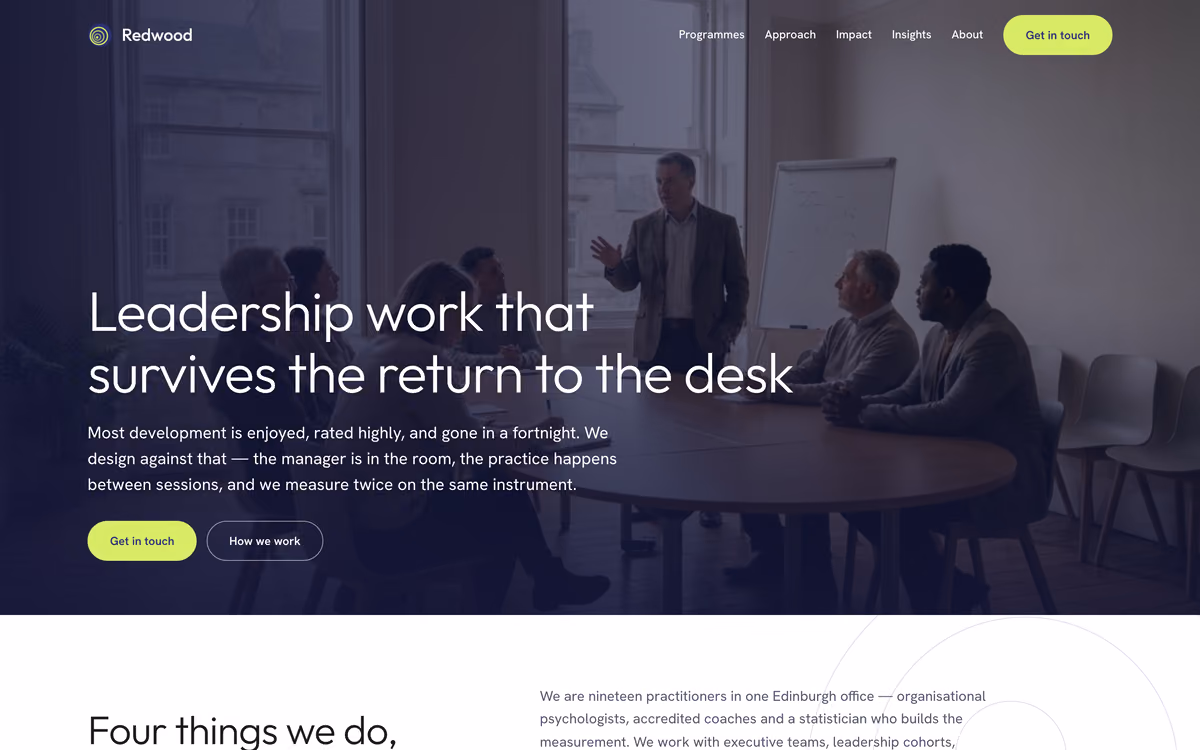 The Redwood Leadership home page: “Leadership work that survives the return to the desk” over a photograph of a coaching session in a bright meeting room